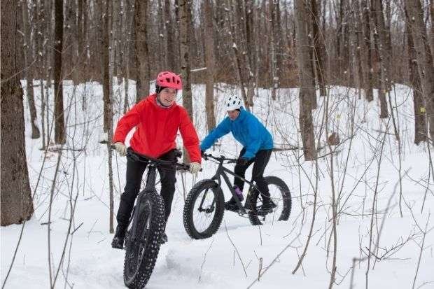 Couple biking in the snow after learning how to keep ears warm while cycling