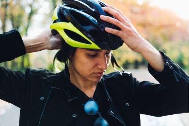 The Best Bike Helmets for Ponytails Out There Woman putting on bike helmet for ponytail