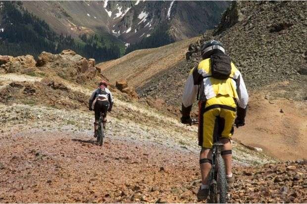 Carbon or Aluminum Mountain Bike: Which Should You Buy? Mountain bikers riding downhill after choosing between carbon or aluminum mountain bike