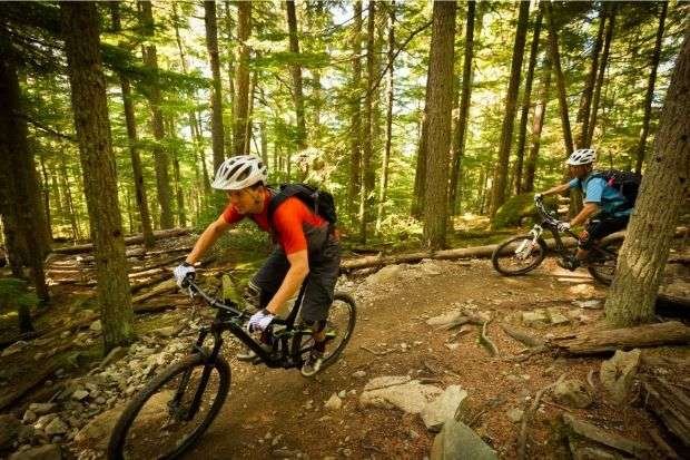 Mountain bikers riding on trail after learning why do mountain bike helmets have visors