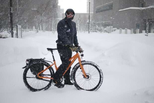 Cyclist riding in the snow on a bike with an internal gear hub after learning if you can add gears to a single speed bike