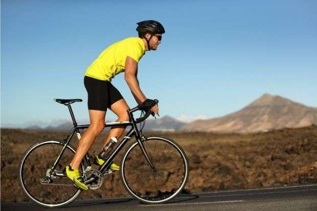 Man riding uphill on bike after learning if you can add gears to a single speed bike