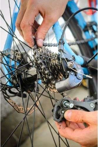 Rider taking apart broken rear derailleur after learning if you can add gears to a single speed bike